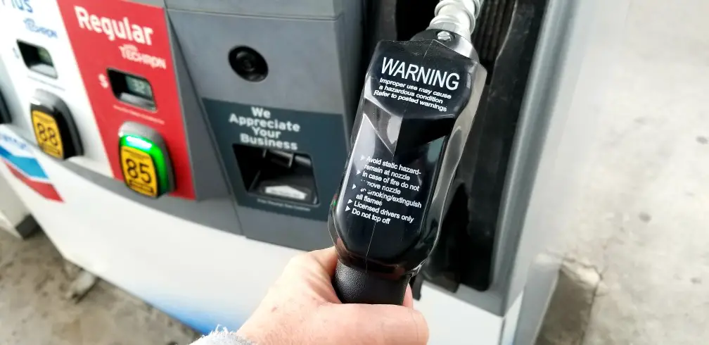 human hand holding gas pump nozzle