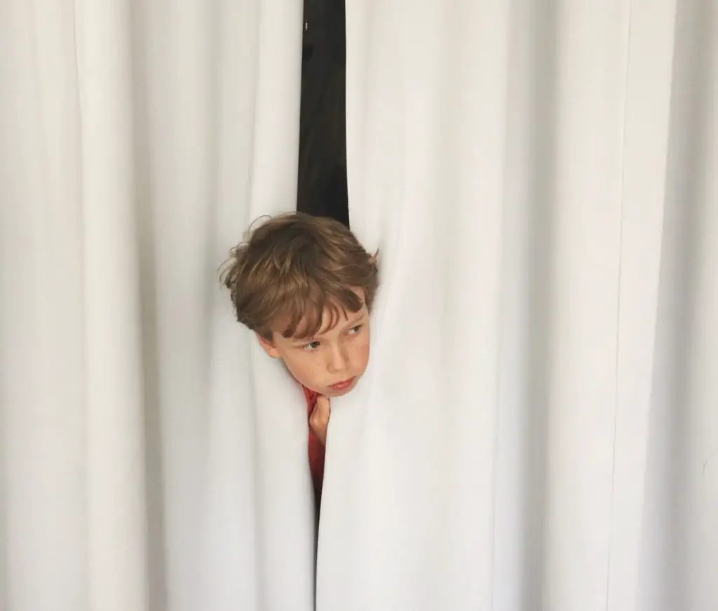 child looking out through curtains